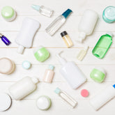 Flat lay composition of empty white and green plastic cosmetic containers, lotion bottles, and cream jars ready for custom brand logo printing.